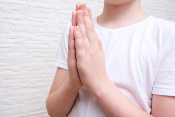 istock A boy showing gratitude gesture on white background, he is hopeful while praying 1340558331