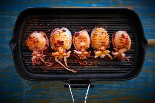 Grilled cuttlefish squid in cast iron grill on wood