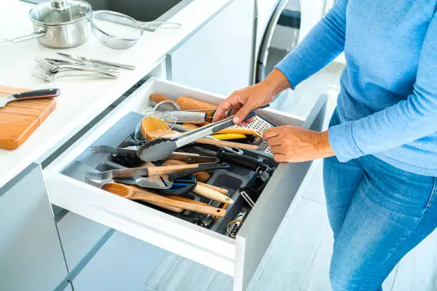 Photo of Woman sorting out messy kitchen drawer