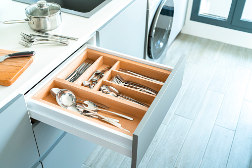 High angle view of an open kitchen drawer with stainless steel cutlery.