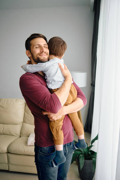 istock Affectionate father embracing his small son at home. 1340560555