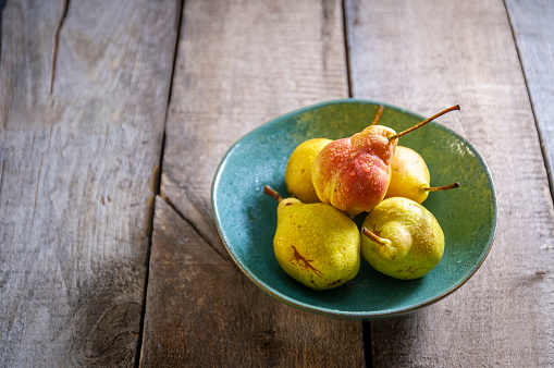 Fresh Pear Fruits in a Bowl on the Kitchen's Wooden Table in Natural condition. Appearing the drops on the fruits.