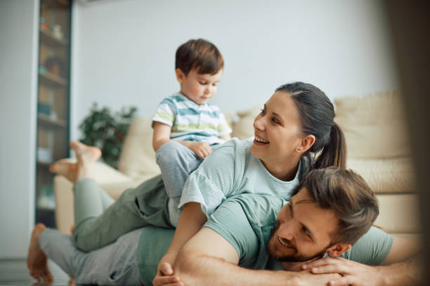 istock Happy family having fun while making human pyramid on the floor at home. 1340560669