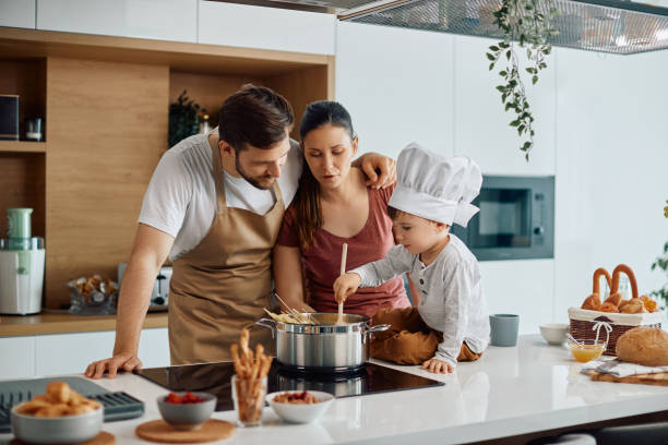 istock Young family cooking spaghetti while making lunch in the kitchen. 1340560739