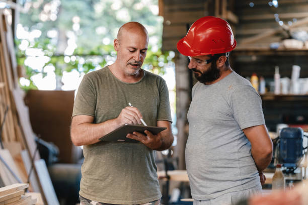 istock Middle Aged Architect Describing His Project To The Carpenter In The Carpentry Workshop 1340563729