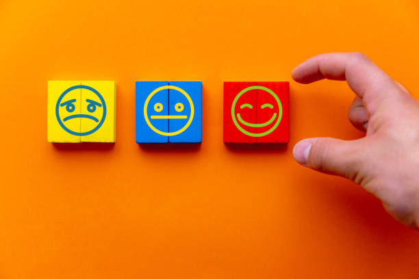 Customer service evaluation and satisfaction survey concepts. The client's hand picked the happy face smile face icon on wooden cube on orange background. Copy space