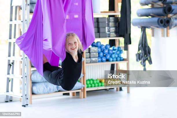 Portrait Young Smiling Girl Practice In Aero Stretching Swing In Purple Hammock In Fitness Club Kids Aerial Flying Yoga Exercises Stock Photo - Download Image Now