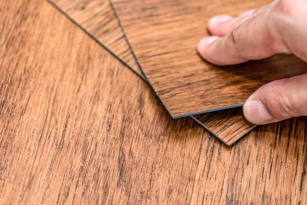 scelta della pavimentazione. concetto di ristrutturazione o costruzione. primo piano di una mano maschile che tiene una piastrella in vinile strutturato. campioni di piastrelle per pavimenti in laminato e vinile - carpet sample immagine foto e immagini stock