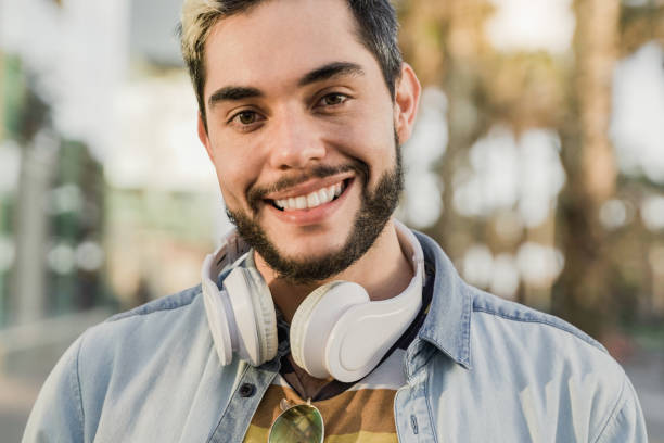 istock Young hipster man smiling on camera with city on background - Focus on face 1340566798