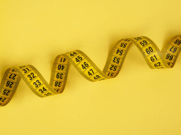 istock Yellow tape measure centimetric with copy space on yellow background 1340569721