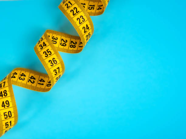 istock Yellow spiral tape measure on blue background 1340574236