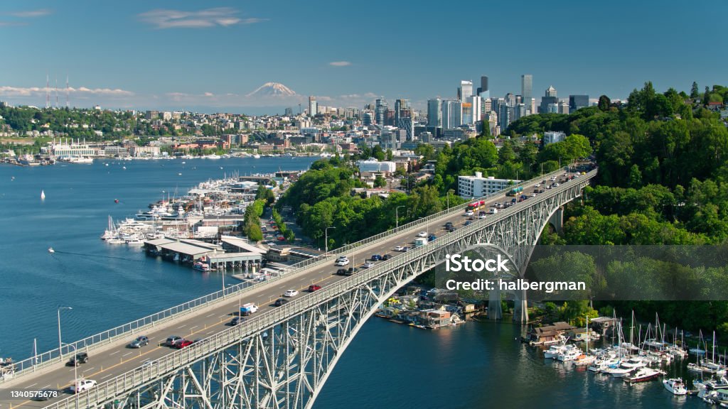 Static Drone Shot of Aurora Bridge with Downtown Seattle Skyscrapers and Mt Rainier in Distance Aerial shot of Seattle, Washington on a sunny day in summer. The Aurora Bridge and the Fremont Bridge carry traffic between Queen Anne and Fremont across the Lake Washington Ship Canal as it opens up into Lake Union. Seattle Stock Photo