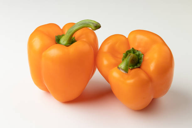 istock Two orange bell peppers isolated on white background 1340576292