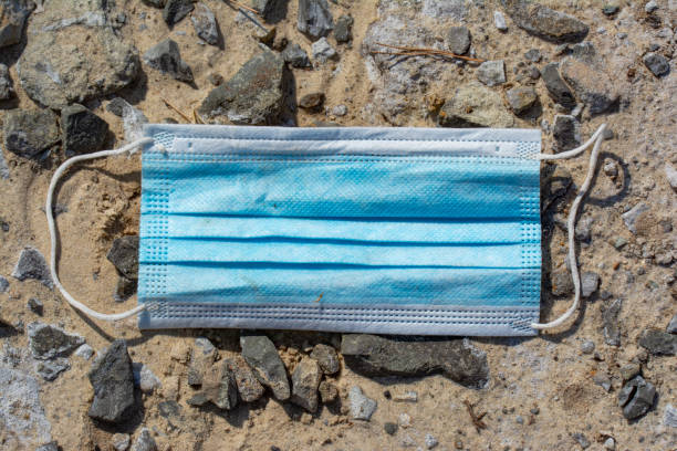 istock Blue surgical face mask lying on a dirt road with rubble. 1340579505