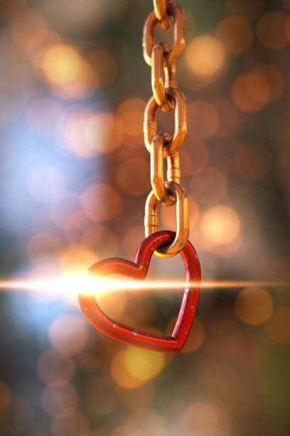 istock Hanging gold chain with a red heart element in front of a shiny defocused background. 1340580411