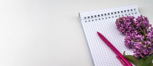 istock Spiral notebook and pen. Notepad with pen and flowers. Notebook lilacs on white background. 1340583299