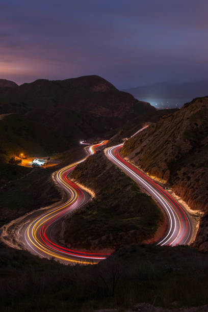 istock High angle view of light trails on a U-shaped road at night with a mountain background 1340584874