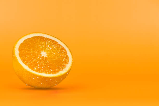 istock sliced orange fruit with drops on the peel, on an orange background 1340585428