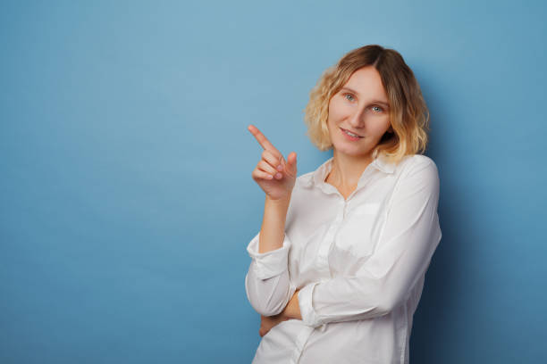 istock Happy young woman pointing a finger away 1340586499