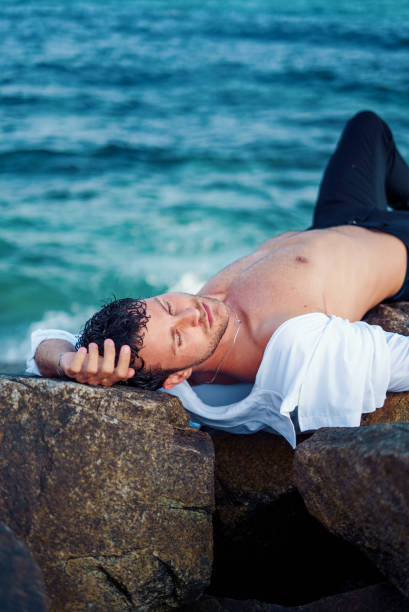 istock Relaxed man lying on rock on beach 1340588405