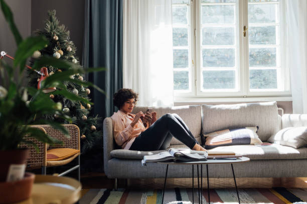 bella donna che usa il telefono cellulare a casa - window christmas christmas tree winter foto e immagini stock
