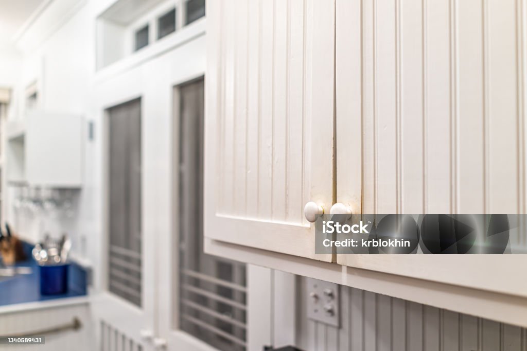 Modern vintage beach cottage style white wooden cabinets in house home closeup with background of kitchen room and window Cabinet Stock Photo