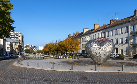 Troyes, France, October 22, 2020: View of the Quai des Comptes de Champagne on the Canal du Trévois with the monument Heart of Troyes. The stainless heart symbolises the romantic side of the old town and serves as meeting point.