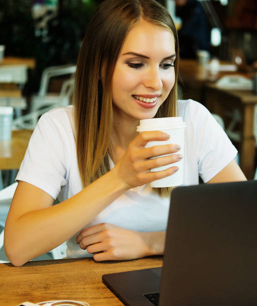 istock young blond woman drinking coffee/tea and using laptop in a coffee shop 1340594551