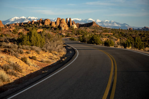 Road Curves Toward The Sand Dune Arch Area of Arches Road Curves Toward The Sand Dune Arch Area of Arches National Park la sal mountains stock pictures, royalty-free photos & images