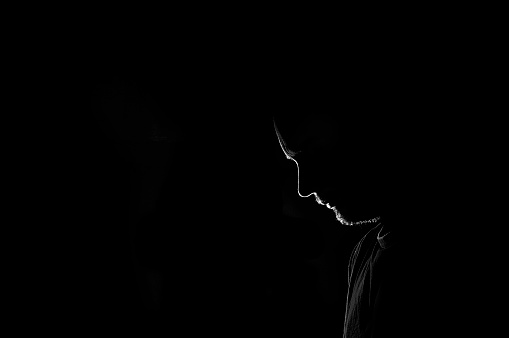 Male profile silhouette. sad or loneliness young man on black background. Unrecognizable person looking down. Image with copy space.