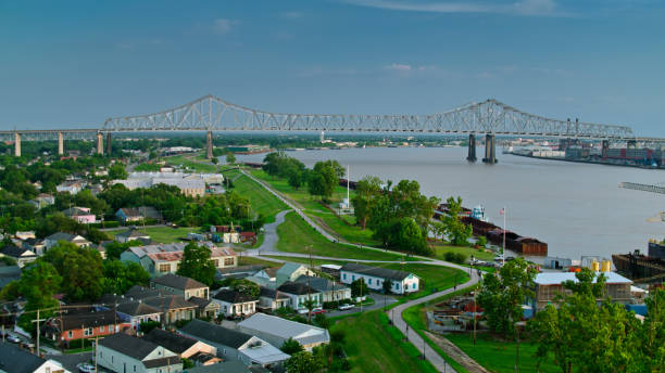 Mississippi River Train on Algiers Point and Crescent City Connection Bridge in New Orleans - Aerial Aerial shot of New Orleans, Louisiana at sunset on a summer evening, flying over the residential neighborhood of Algiers and looking along the west bank of the Mississippi towards the Crescent City Connection Bridge. algiers stock pictures, royalty-free photos & images
