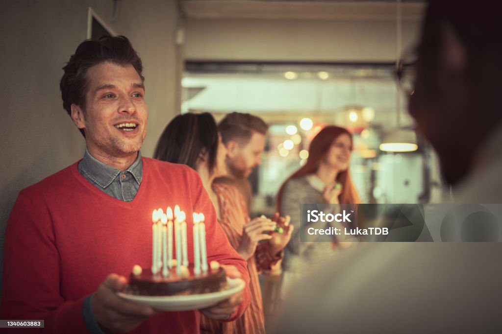 B-day surprise for a colleague Depicting a festive scene at the office. One of the employees is having a B-day and his colleagues decided to surprise him with a cake. Friendship Stock Photo