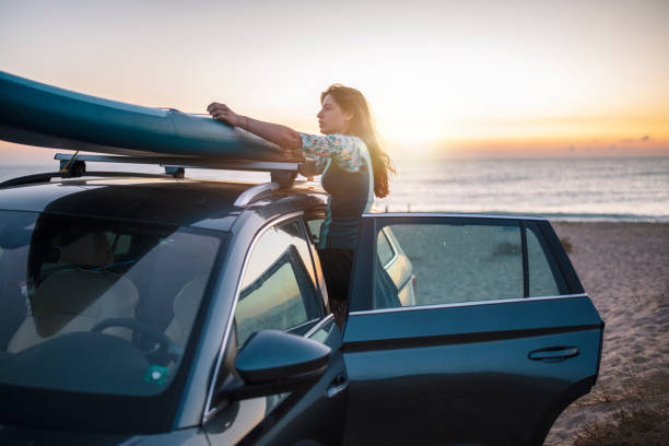 istock Woman Unloading Surfbard From Car To Ride In The Morning. 1340604442