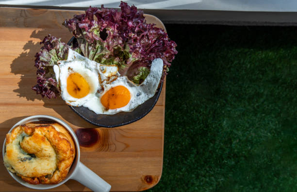 istock Breakfast with Spinach brioche, Two fried eggs, Oak Leaf lettuce on wooden table at balcony. 1340604533