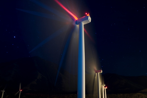 Time exposure of large wind generators at night.