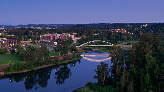 Aerial shot of Salem, Oregon on a summer night, looking across the Willamette River and Riverfront City Park towards downtown buildings. \n\nAirspace authorization was obtained from the FAA for this operation.