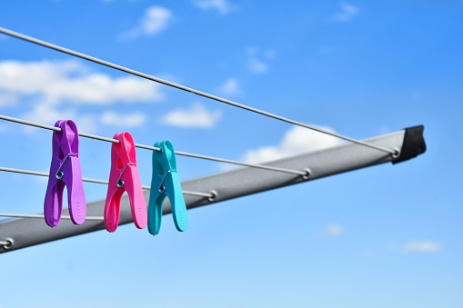 An image of three very colorful cloths pins on a clothesline.