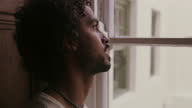 istock 4k video footage of a young man looking out the window at home 1340611940