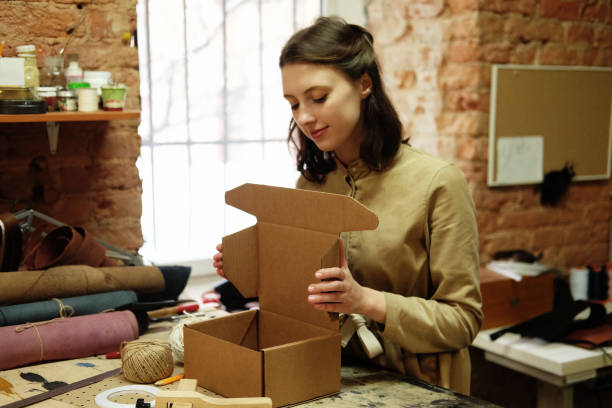 mujer dobla la caja de embalaje en el taller de costura - sewing box fotografías e imágenes de stock