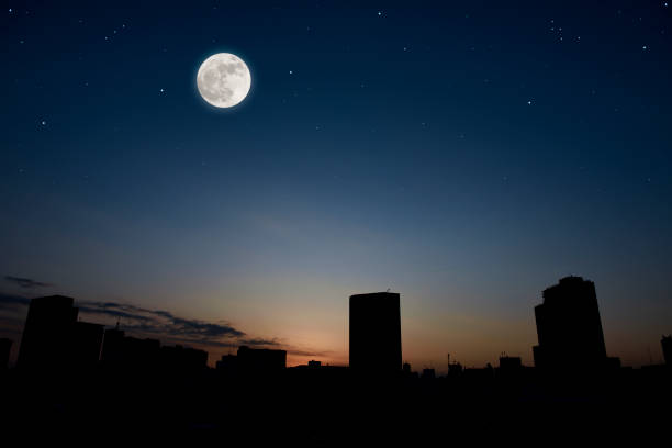 istock Full moon rising over the buildings at dusk. 1340621628
