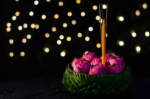 Selective focus on pink lotus flower decorates on banana leaves Krathong with bokeh lights background for Thailand full moon or Loy krathong festival.