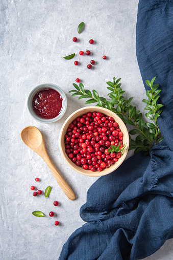 juicy forest lingonberry with handmade jam  in a wooden bowl on white table with blue napkin. Concept homemade healthy food. Top view and copy space image