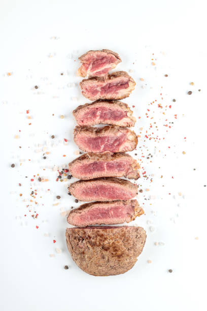 Fried cooked beef steak cut into pieces with spices on a white background. Top view.