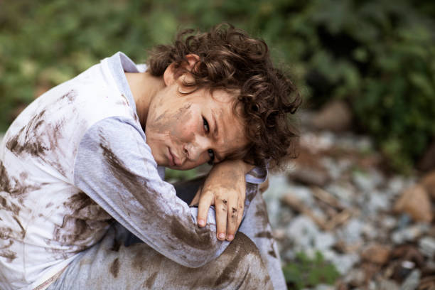 poor dirty boy bowed his head to his knees. High quality photo