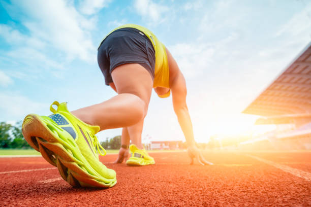 coureur utilisant le bloc de départ pour commencer sa course sur piste de course. athlète coureur pieds courant sur l’hippodrome.  jeune homme faisant du jogging dans un stade d’athlétisme. - starting block dathlétisme photos et images de collection