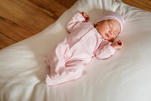Portrait of a newborn baby lying on a bed in the living room