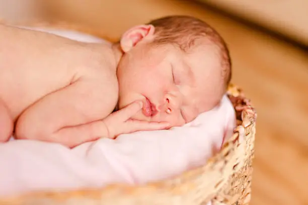 Sleeping cute newborn baby sleeps on a round crib.