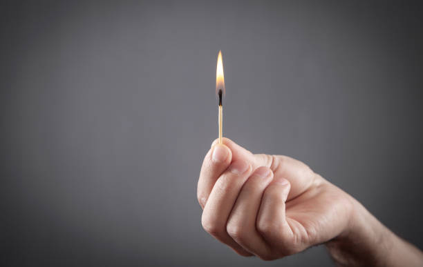 istock Burning match in male hand in grey background. 1340650080