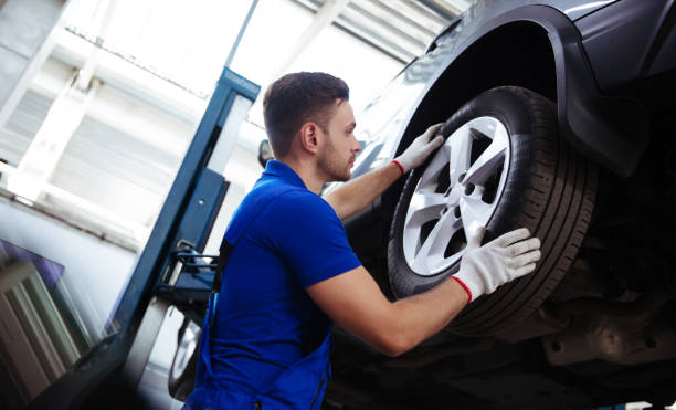 istock Handsome professional car mechanic changes a wheel on a car or carries out a tire change at a specialized auto repair center 1340652018