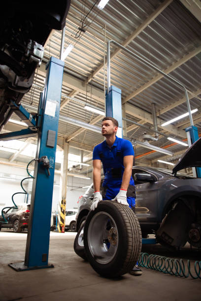 istock Handsome professional car mechanic changes a wheel on a car or carries out a tire change at a specialized auto repair center 1340652092